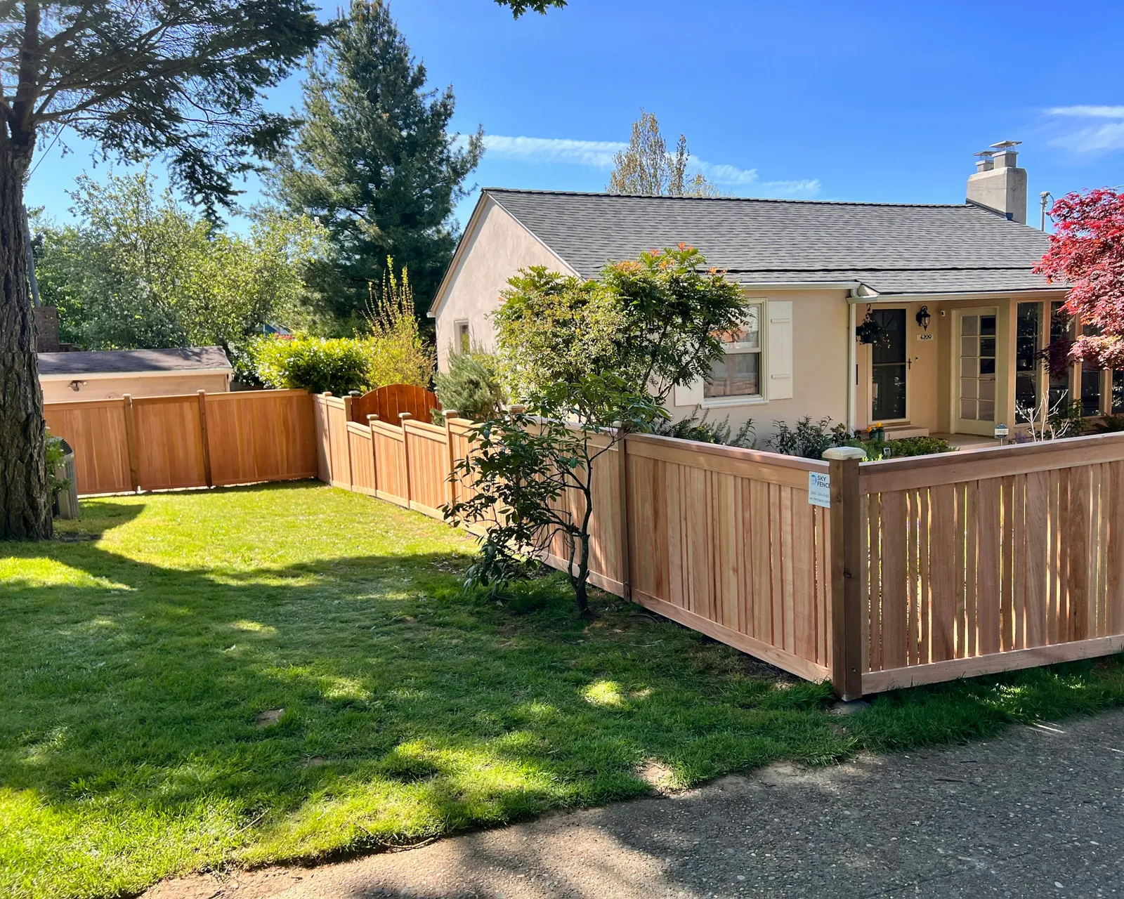 A new cedar privacy fence with a lattice top around a backyard lawn